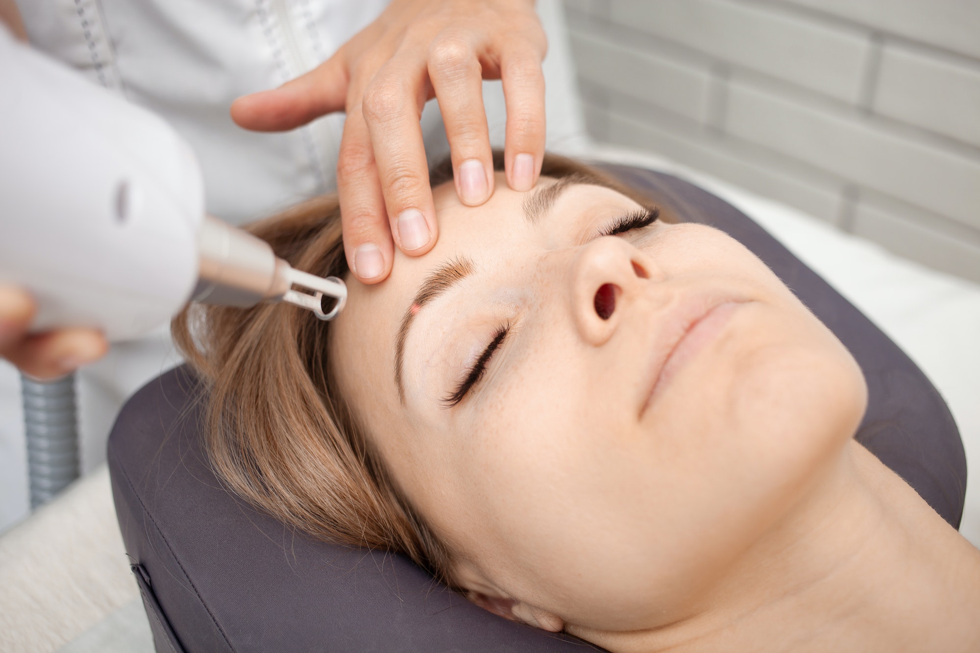 cosmetologist removes permanent makeup, eyebrow tattooing with laser.
